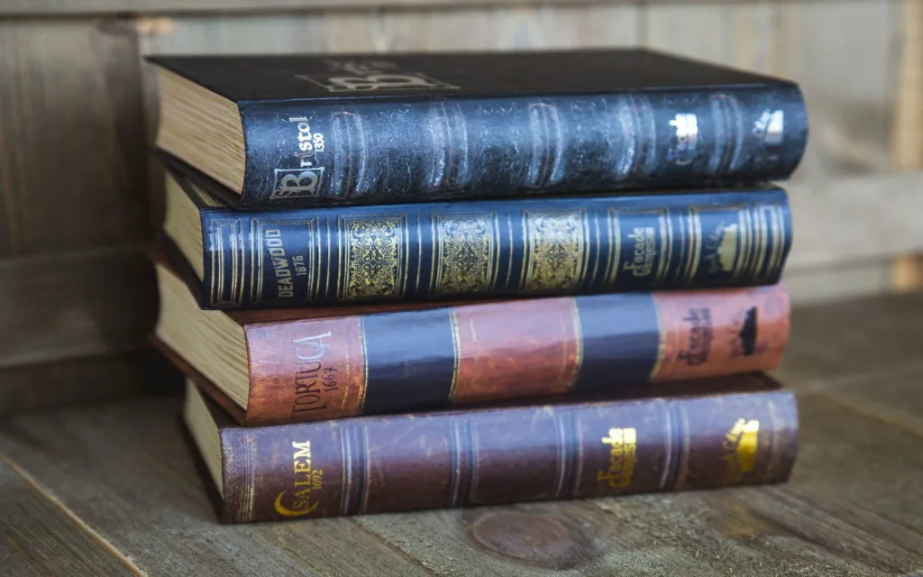 Cajas de Bristol 1350, Deadwood 1876, Tortuga 1667 y Salem 1692 apiladas como libros antiguos