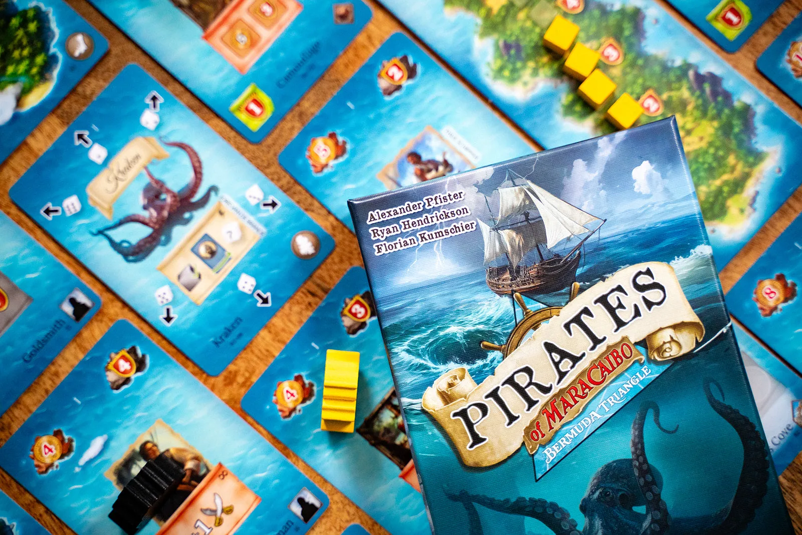 Caja de Pirates of Maracaibo: Bermuda Triangle sobre cartas de tesoros y barcos de madera